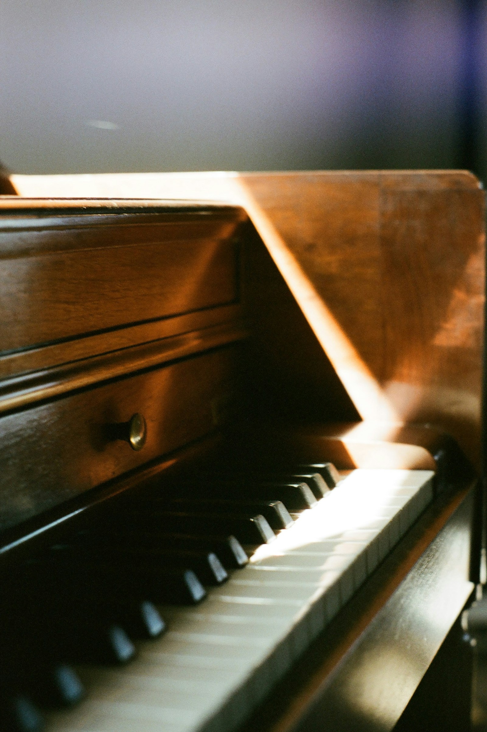 Sunlight falling across the keys of a wooden upright piano